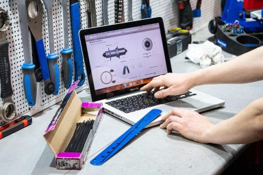 Travailleur indépendant Un homme utilise un ordinateur portable sur un bureau d'atelier avec des outils en arrière-plan.