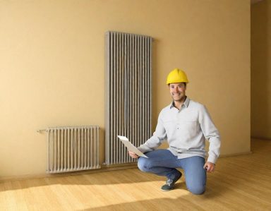 Artisan Un homme en casque de chantier inspecte une pièce vide avec un radiateur.